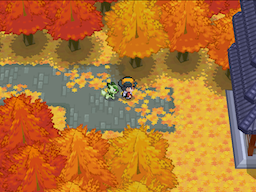 The player walking a narrow river path through autumn trees beside a grey building