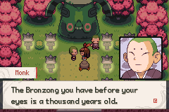 A monk in front of a huge green Bronzong statue ringed by stone lanterns and pink blossom