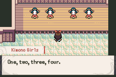 Four kimono girls standing in a row on a wooden stage above a tiled floor