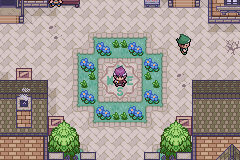 Walking through a small town square bordered by hedges and flower beds