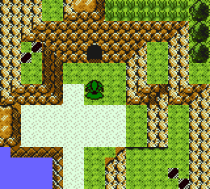 A grassy coastal gully surrounded by steep cliffs, the player standing near a cave entrance