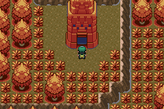 The player standing on a dirt path outside a tall red brick tower, surrounded by rows of orange and gold autumn trees