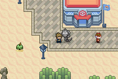 A paved plaza in front of a Pokémon Centre, with a Nidoking, a passer-by and a Grimer on the grass below